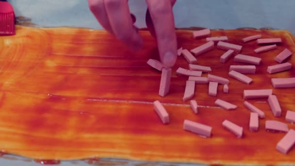 Je fais une pizza maison. Homme met un morceau de saucisse sur la pâte avec de la sauce, main close-up . — Video