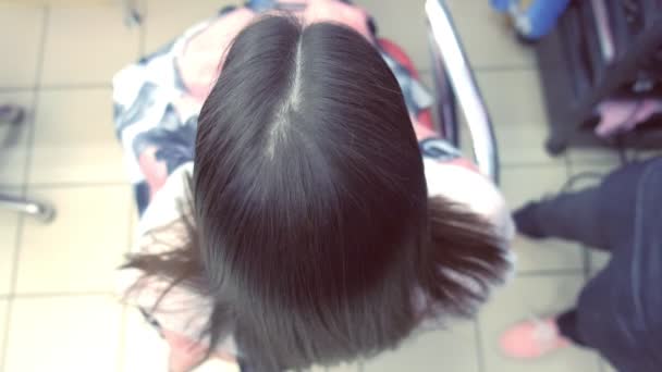 Coiffeur redresse les cheveux brun foncé de belle femme en utilisant des pinces à cheveux dans le salon de beauté. Gros plan sur les cheveux . — Video