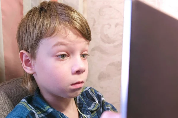 Junge schaut auf Computerbildschirm, der zu Hause auf dem Sofa sitzt. — Stockfoto
