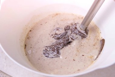 Mix blender ile sıvı koyu çikolata ve beyaz bir kase krem. Yakın çekim görünümü.