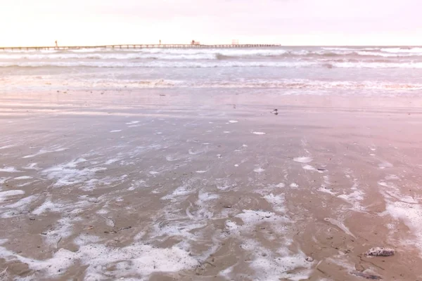 Wellen im Meer. wunderschöne Meereslandschaft mit Pier, Sandstrand bei Sonnenuntergang. — Stockfoto