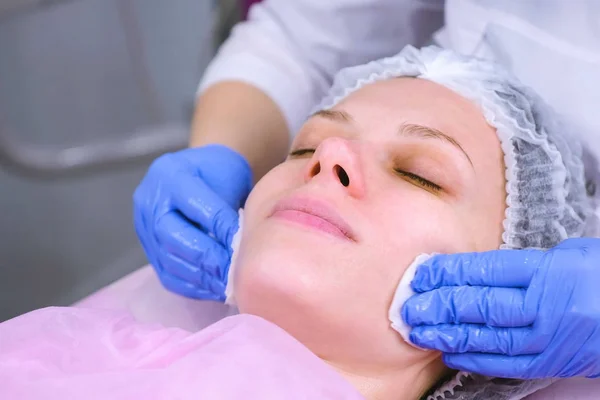 Schoonheidsspecialiste wast womans gezicht met behulp van katoen kussentjes. Voorbereiding voor een reiniging gezicht. — Stockfoto