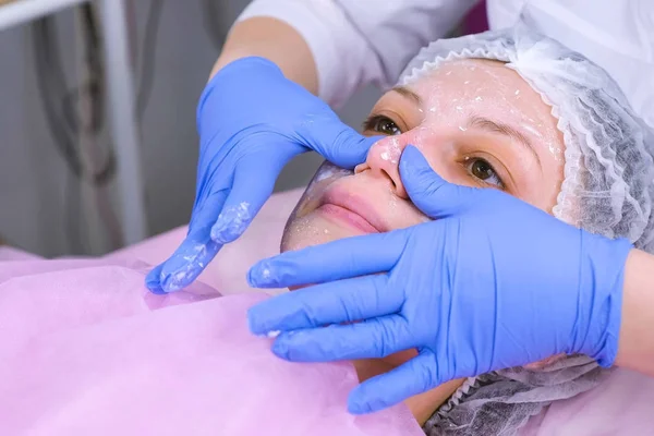Schoonheidsspecialiste zet masker op dames gezicht. Reiniging gezicht. — Stockfoto