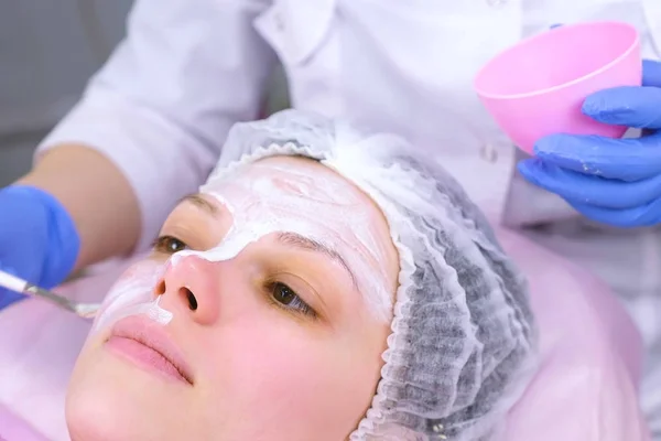 Schoonheidsspecialist zet masker op dames gezicht met borstel. Hydraterende gezicht. Gezicht close-up. — Stockfoto