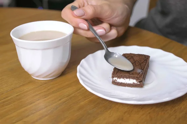 Frau gießt Kaffee auf das Stück Schokoladenkuchen. Hand in Hand. — Stockfoto