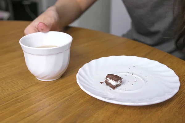 Frau isst ein Stück Schokoladenkuchen und trinkt Kaffee. Hand in Hand. — Stockfoto