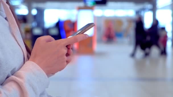 Kobieta na lotnisku z telefonu komórkowego w jej ręce, czekając na jej lotu, widok z boku, ręce zbliżenie. — Wideo stockowe