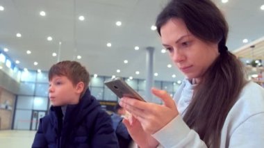 Onun oğlu iade çevrimiçi kayıt Havaalanı salonunda cep telefonunda kadınla.