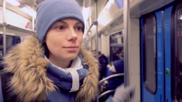 La mujer monta en un vagón subterráneo con ropa de invierno. La vida cotidiana de un habitante de la ciudad . — Vídeos de Stock
