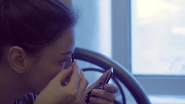 Woman puts makeup, paints her eyebrows with a brush in front of a small mirror. — Stock Video