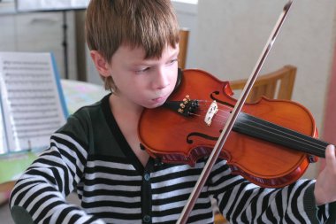 8 yaşında çocuk evde notları kullanarak keman çalıyor.