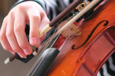 Çocuklar ellerinde keman. Çocuk keman çalmayı öğreniyor. Keman dizeleri sağ taraftan parmakları ayarını düzeltmek.