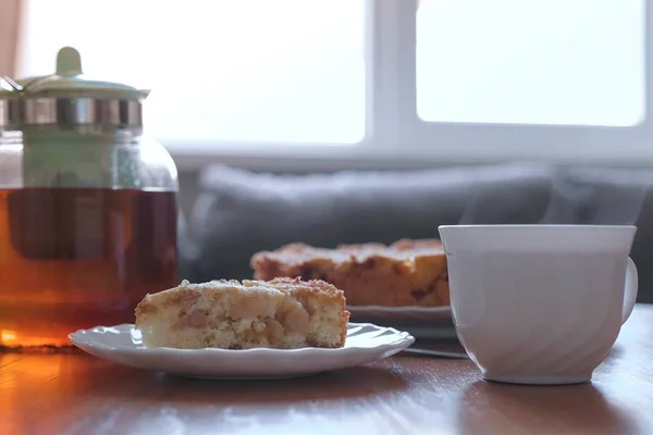 テーブルの上の自家製アップルパイと熱いお茶のスライス。アップルパイ、ティーポット、紅茶のカップ. — ストック写真