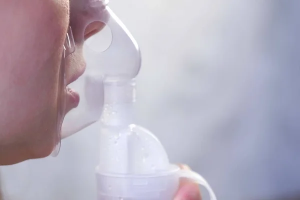 Nebulizatör ve astım tedavisi için kullanın. Genç kadın inhaler maskesi teneffüs edilmesi. Yakın çekim burun ve dudaklarını maskesindeki, yan görünüm. — Stok fotoğraf