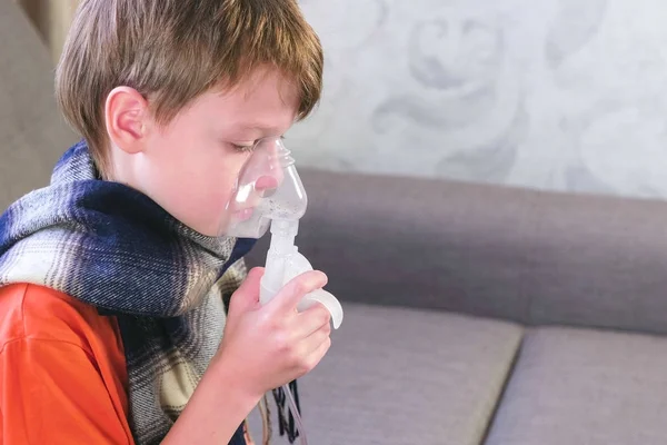 Больной милый мальчик вдыхает через маску ингалятора. Используйте для лечения ингалятор и распылитель. Вид сбоку . — стоковое фото
