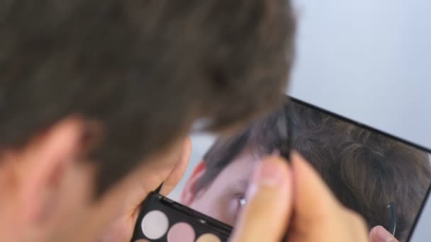 Молодий чоловік вибиває брови пінцетом перед дзеркалом вдома . — стокове відео