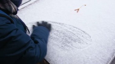 Çocuk kar tablo tarafından sıcak eldiven elleriyle sallıyor. Eller yakın çekim.