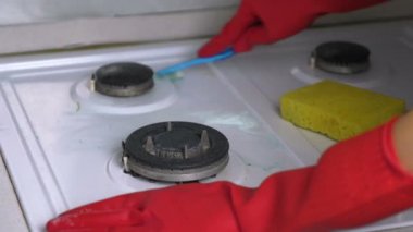 Kırmızı lastik eldiven yıkar kirli gaz sobası bir fırça ve sünger ile kadının eller.