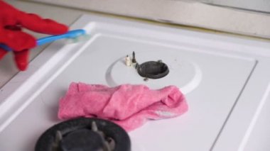 Kırmızı lastik eldiven yıkar kirli gaz sobası bir fırça ve sünger ile kadının eller.
