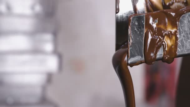 Liquid dark milk chocolate pours out of the tube in Chocolate tempering machine. Close-up view. — Stock Video