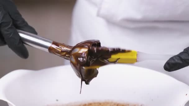 Nettoyage d'un chocolat liquide du mélangeur avec une spatule. Vue rapprochée . — Video