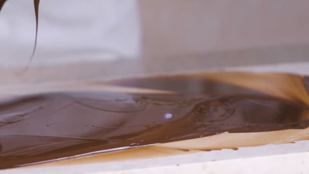 Tempering melted chocolate on natural stone. Womans hands and spatula close-up. — Stock Video