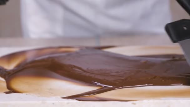 Tempering melted chocolate on natural stone. Womans hands and spatula close-up. — Stock Video