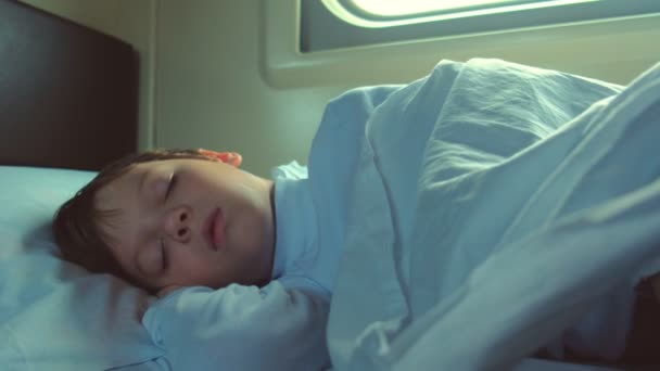 Drengen sover i bilen på et tog i bevægelse tidligt om morgenen. . – Stock-video