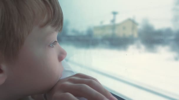 Menino está olhando na janela em movimento trem na paisagem de inverno . — Vídeo de Stock