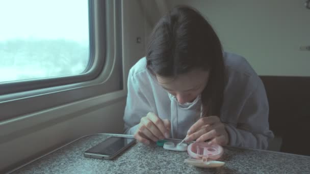 Vrouw zet contactlenzen in de ogen reizen per trein op een lange afstand. — Stockvideo