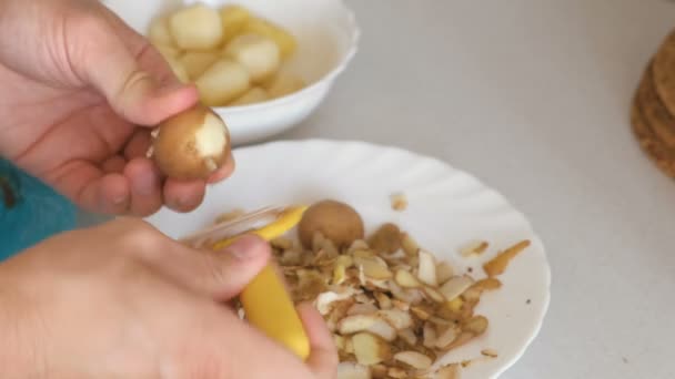 Чоловічі руки очищають картоплю від жовтого шкірки . — стокове відео