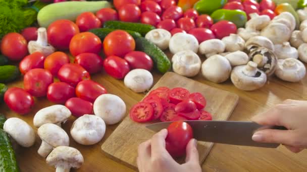 Womans manos está cortando tomates en la caldera de madera en la mesa de la cocina. Vista lateral . — Vídeo de stock