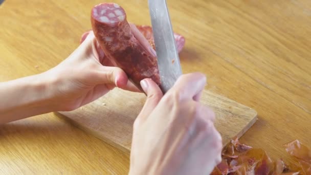 Les mains des femmes épluchent la saucisse fumée de la peau . — Video