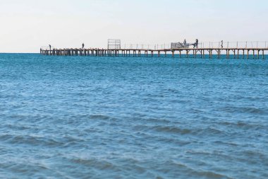 İnsanlar eski ahşap iskele denizin üzerinde yürüyor. Yan görünüm.