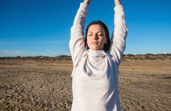 Kvinnan är stretching gör yoga på sandstranden med vågor. — Stockfoto