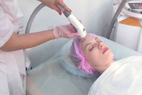 Lymfedrainage massage Lpg apparaat proces voor gezicht. Therapeut schoonheidsspecialiste maakt een verkwikkende gezichtsmassage voor de vrouw in de kliniek. Schoonheid en bodycare concept. — Stockfoto