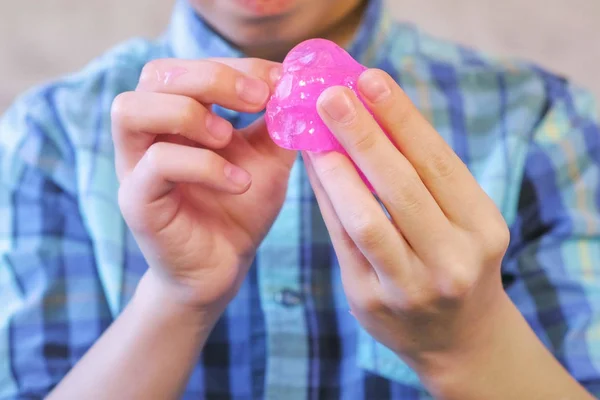 Las manos de los chicos tienen un limo rosado. Chico juega con limo . — Foto de Stock