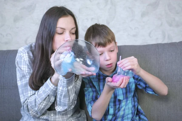 Мама и сын надувают большие пузыри из слизи. Играть со слизью . — стоковое фото