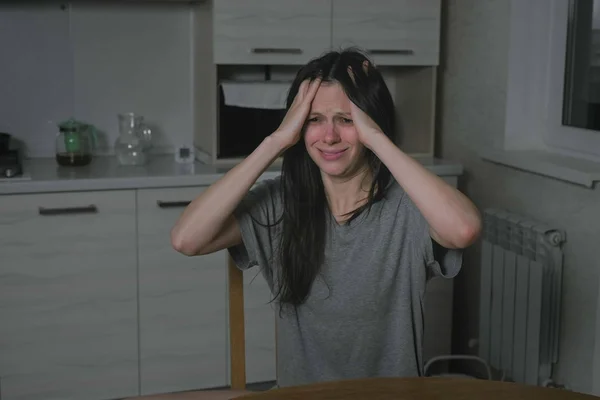 Vrouw met hoofdpijn in de keuken bij nacht. Slapeloosheid en depressie. — Stockfoto