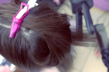 Kuaför düzlüklerde koyu kumral saç maşa güzellik salonunda kullanarak kadının. Saç yakın çekim.