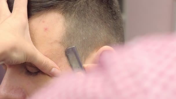 Парикмахер бреет волосы на висках мужчин острой бритвой. Стилисты разводят руками крупным планом. — стоковое видео