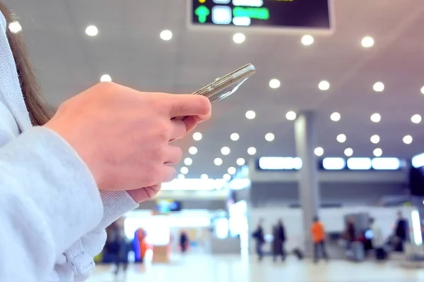 Регистрация женщины в режиме онлайн на мобильном телефоне в зале аэропорта, руки с крупным планом смартфона . — стоковое фото
