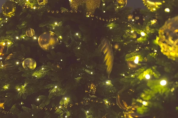 Bolas de Navidad de color oro y guirnaldas con bulbos en las ramas del árbol de Navidad, vista de cerca . — Foto de Stock
