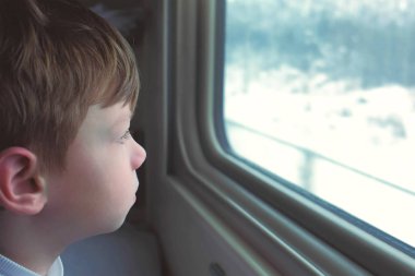 Çocuk tren kış manzara üzerinde hareketli penceresinde arıyor.
