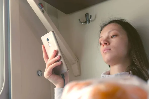 Moe vrouw is het lezen van een boek in de smartphone op een lange afstand trein. — Stockfoto