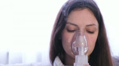 Nebulizatör ve astım tedavisi için kullanın. Genç kadın inhaler maskesi teneffüs edilmesi. Yakın çekim yüz, önden görünüm.