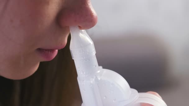 Per il trattamento utilizzare nebulizzatore e inalatore. Giovane donna che inala attraverso l'ugello inalatore per il naso. Naso da primo piano . — Video Stock