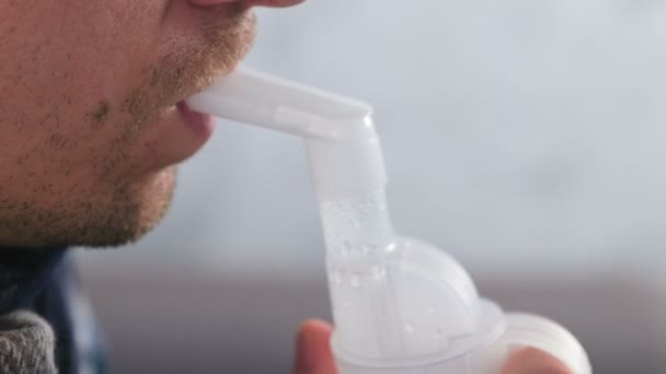 Use nebulizador e inhalador para el tratamiento. Hombre enfermo inhalando a través de la boquilla del inhalador para la garganta. Vista lateral de los labios y la nariz . — Vídeos de Stock