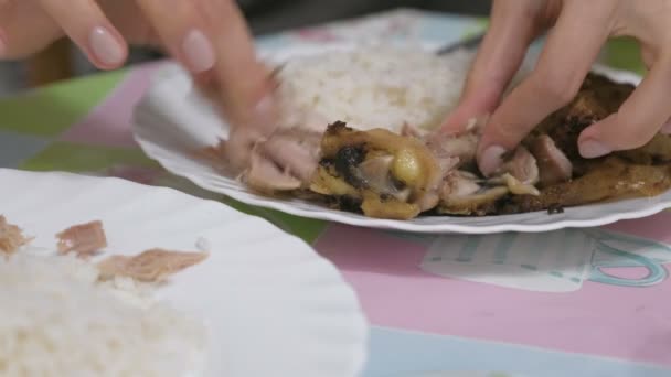 Woman tearing apart fried chicken with his hands over the plate. — Stock Video