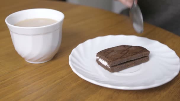 Woman is eating a piece of chocolate cake and drinks coffee. Close-up hand. — Stock Video